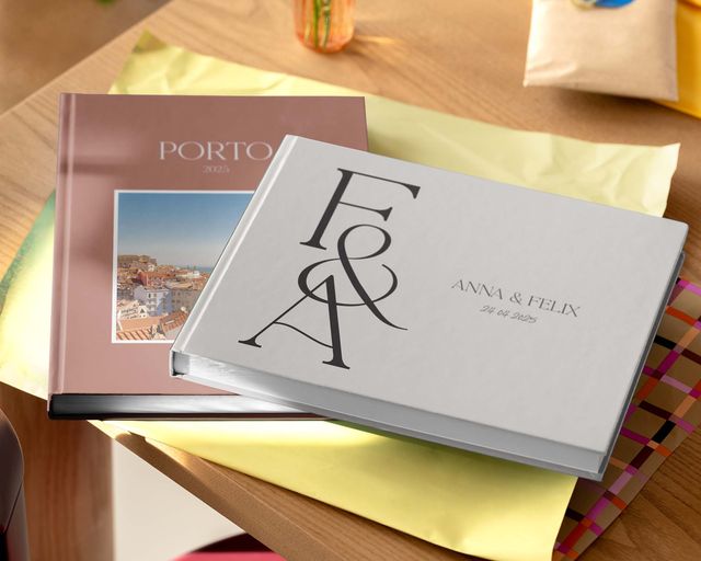 Zwei personalisierte Fotobücher in verschiedenen Größen und Designs auf einem Tisch.