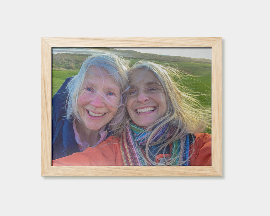 Ein gerahmtes Poster mit dem Foto von zwei lächelnden Frauen.