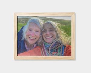 Ein gerahmtes Poster mit dem Foto von zwei lächelnden Frauen.
