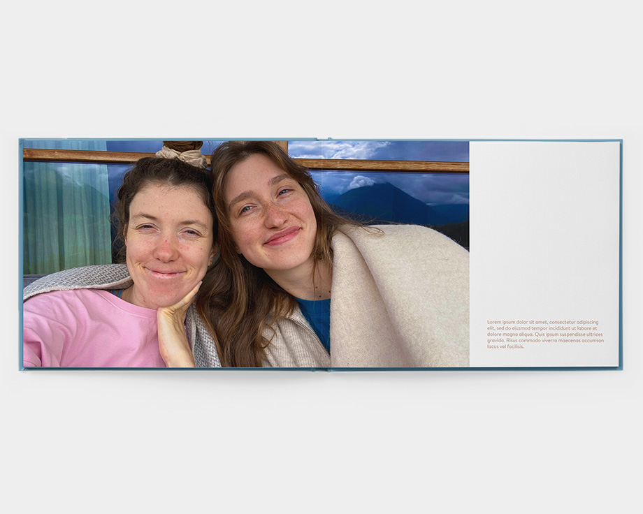 Ein aufgeschlagenes Querformat-Layflat-Fotobuch mit einem Foto von zwei lachenden Frauen.