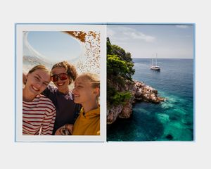 Ein großes Hochformat-Fotobuch mit einem Foto einer Person an einem Bergsee.
